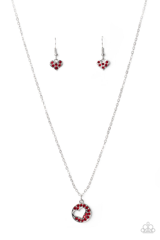 Featuring an airy heart cutout, a glittery red rhinestone encrusted silver disc swings from the bottom of a dainty silver chain below the collar for a romantic flair. 